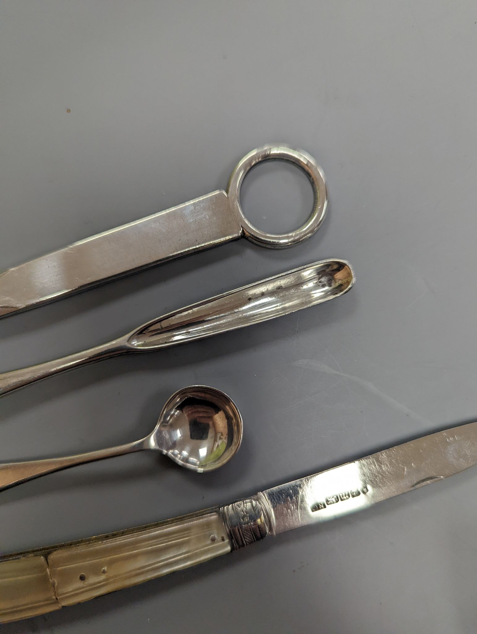 A George VI silver paper knife, London, 1937, a plated toddy ladle, two pairs of silver sugar tongs, damaged silver fruit knife and two other items.